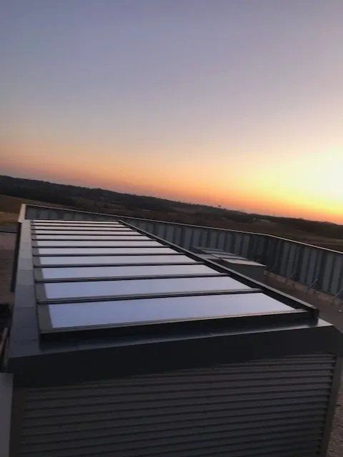 Rooftop with metal skylights at sunset under a clear dusk sky