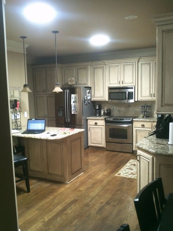 Modern kitchen with wood cabinets, granite countertops, stainless appliances, and a laptop on the island.