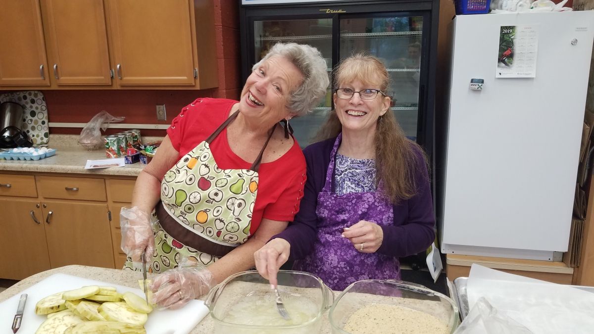 Food and Fellowship 7/11/2019
Two women in aprons smiling while preparing food in a kitchen