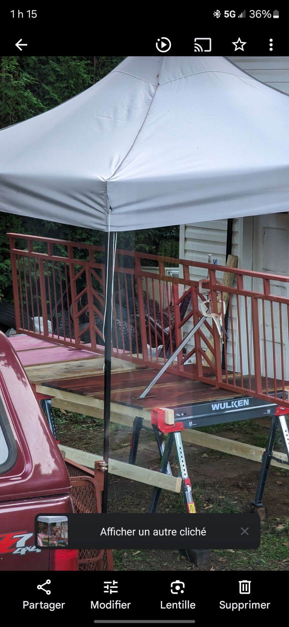 Chantier de construction avec une tente blanche, une balustrade rouge et des outils sur un chevalet.