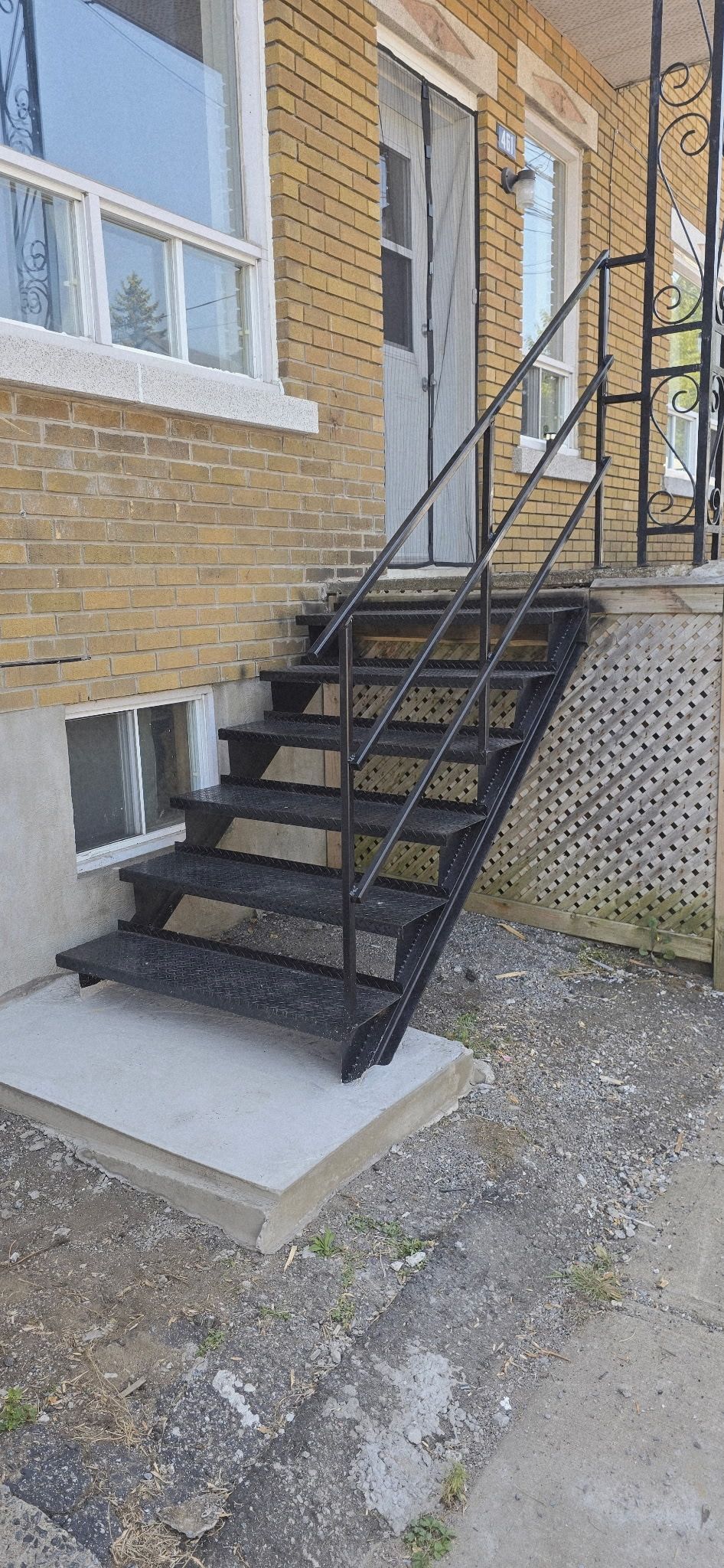Escalier en métal noir menant à une porte sur un bâtiment en briques.