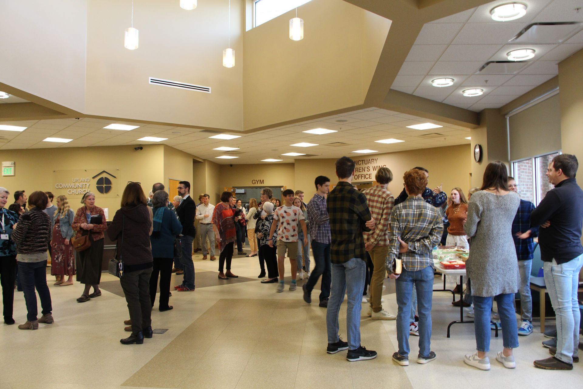 a group of people are standing in a room talking to each other .