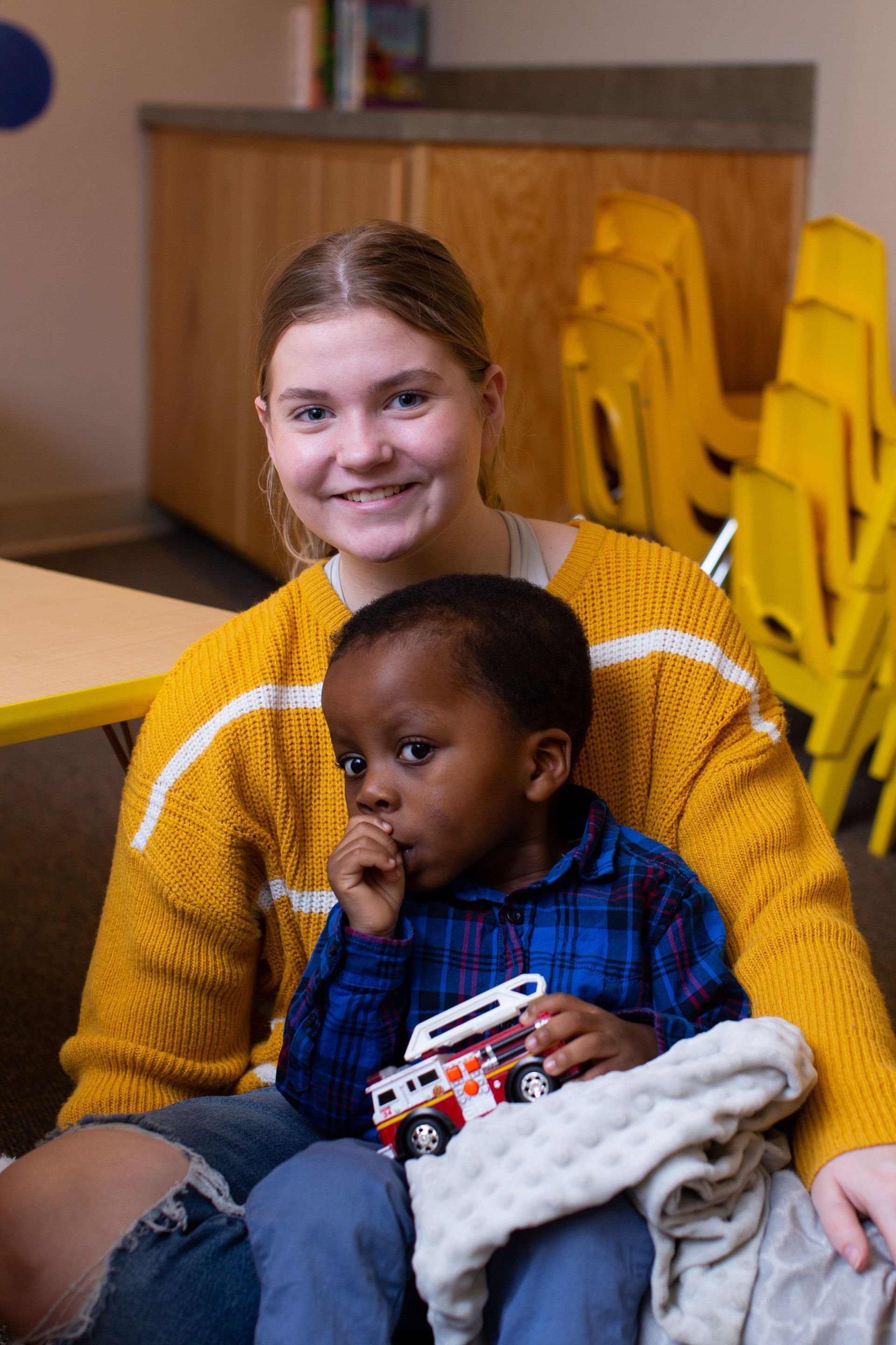 a woman in a yellow sweater is holding a child in her lap .