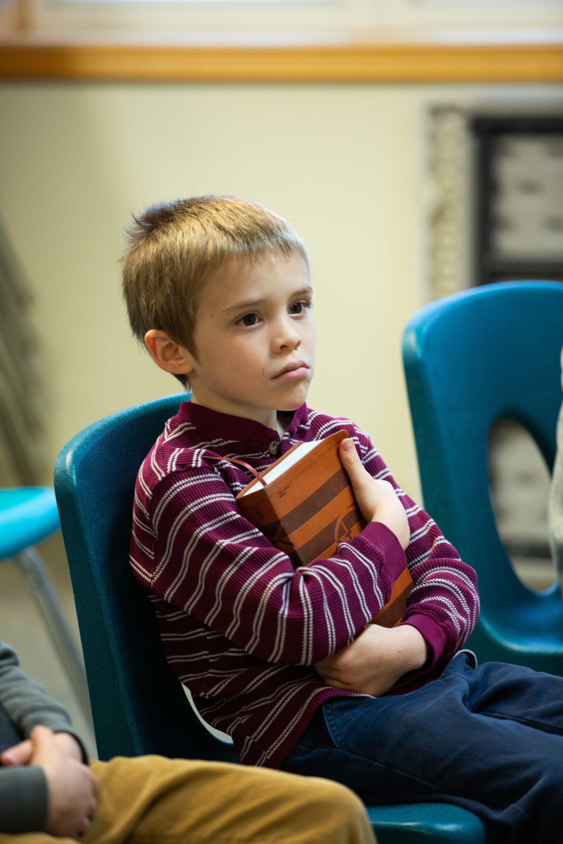 a young boy is sitting in a chair holding a book .