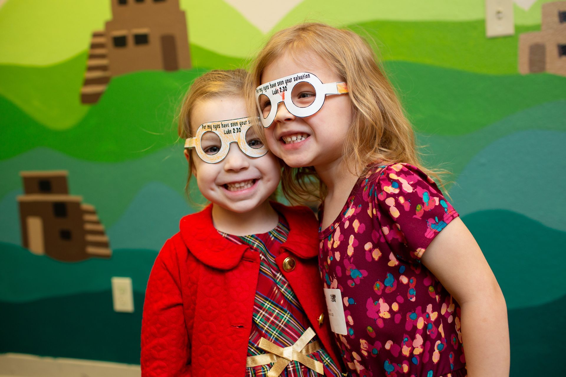 two little girls wearing glasses are posing for a picture .