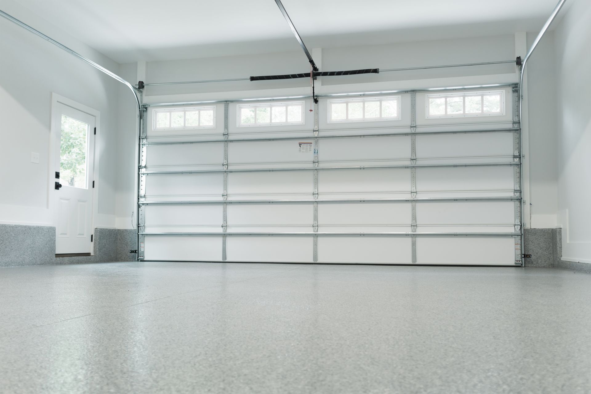Empty white garage interior with closed sectional door and windows above it