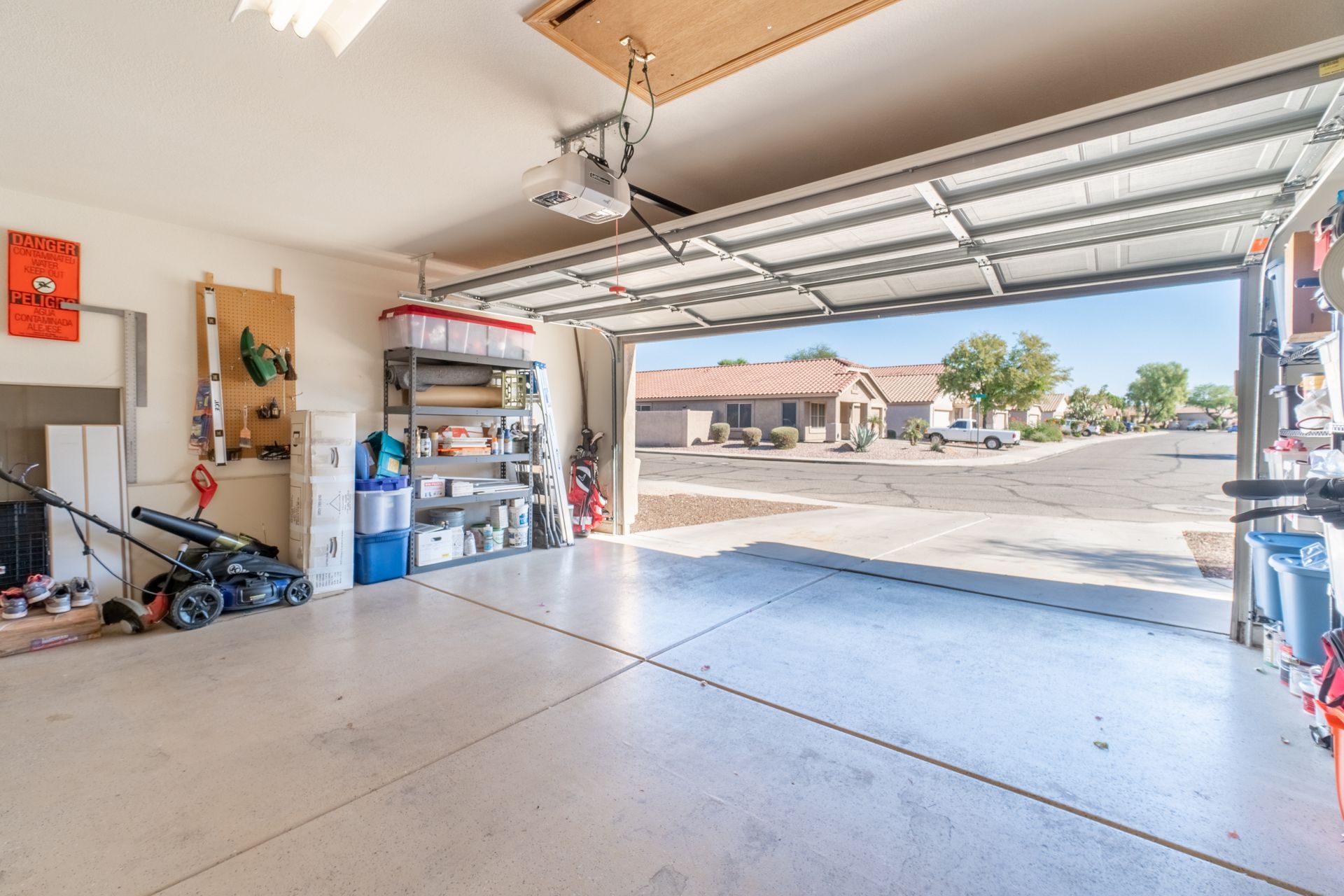 Empty two-car garage with open door, driveway, and suburban street visible outside