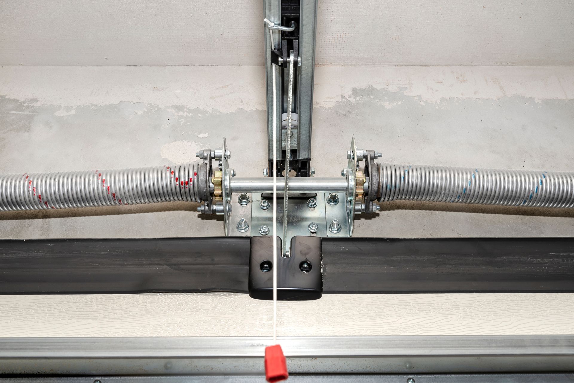 Garage door spring mechanism centered on metal track with horizontal torsion springs and brackets.