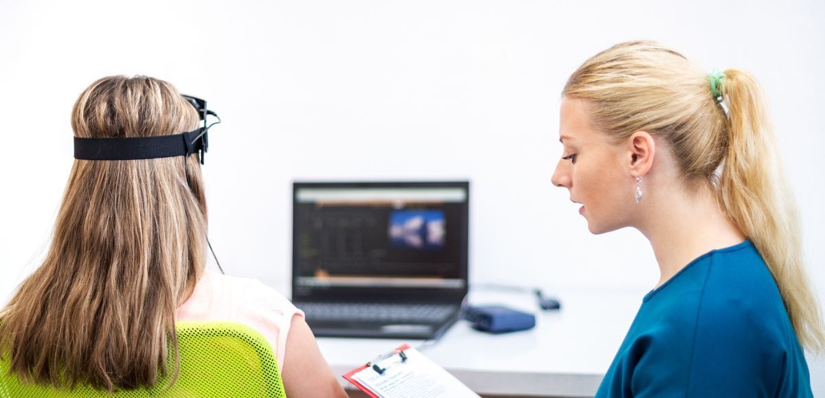 Two people in a meeting, one facing a laptop while the other holds a notepad