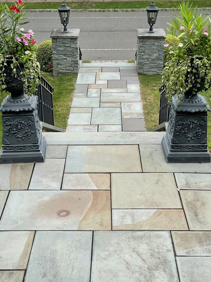 Stone walkway with steps, planters, and lanterns leading to a street entrance