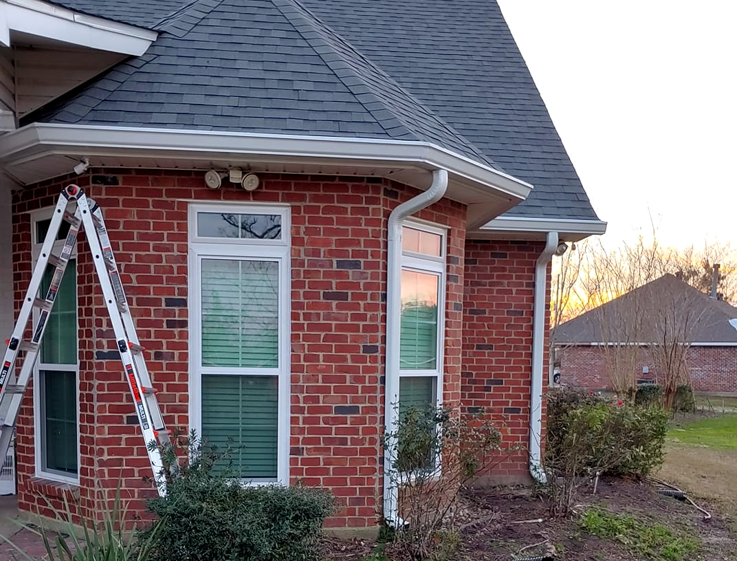 A ladder is sitting on the side of a brick house.