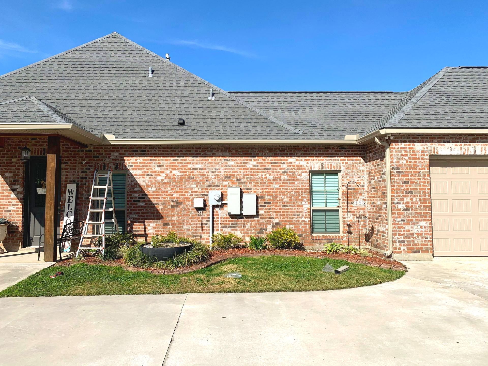 A brick house with a garage and a ladder in front of it.