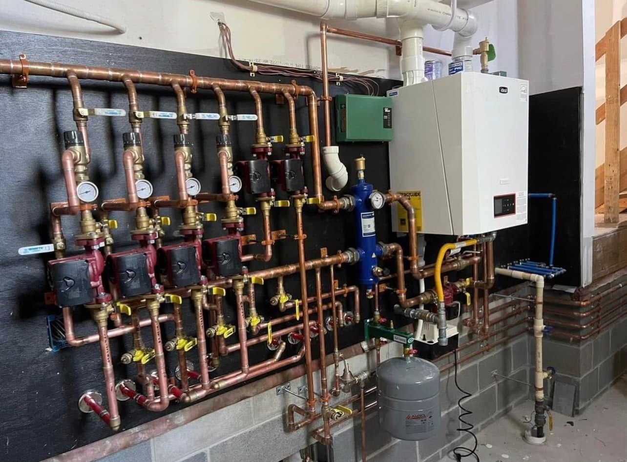 Industrial HVAC mechanical room with copper piping, gauges, pumps, and a white control cabinet