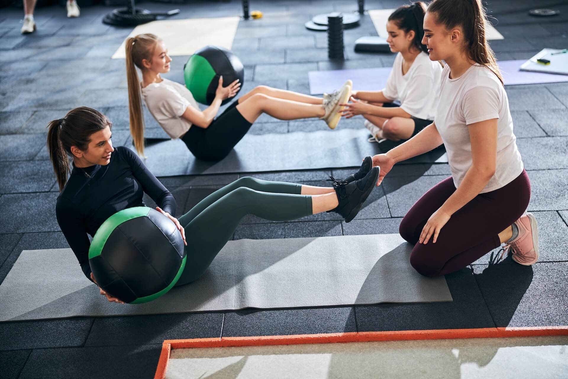 Women doing core exercises with medicine balls in a gym class