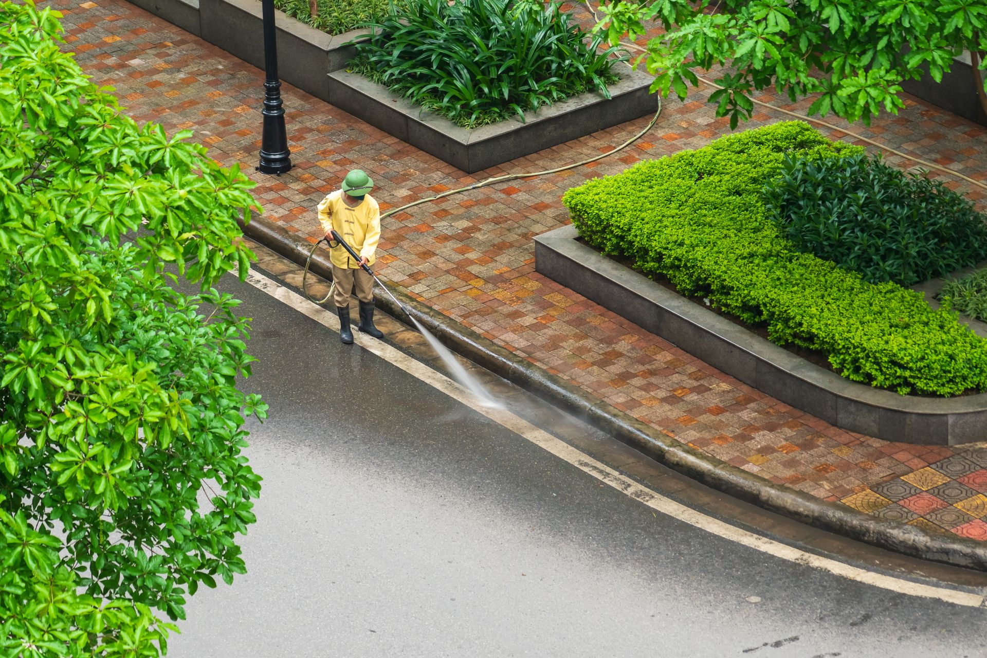 A person is using a high pressure washer to clean a wooden deck.