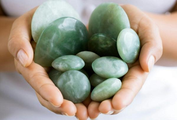 Manos que sostienen piedras y guijarros verdes y lisos.