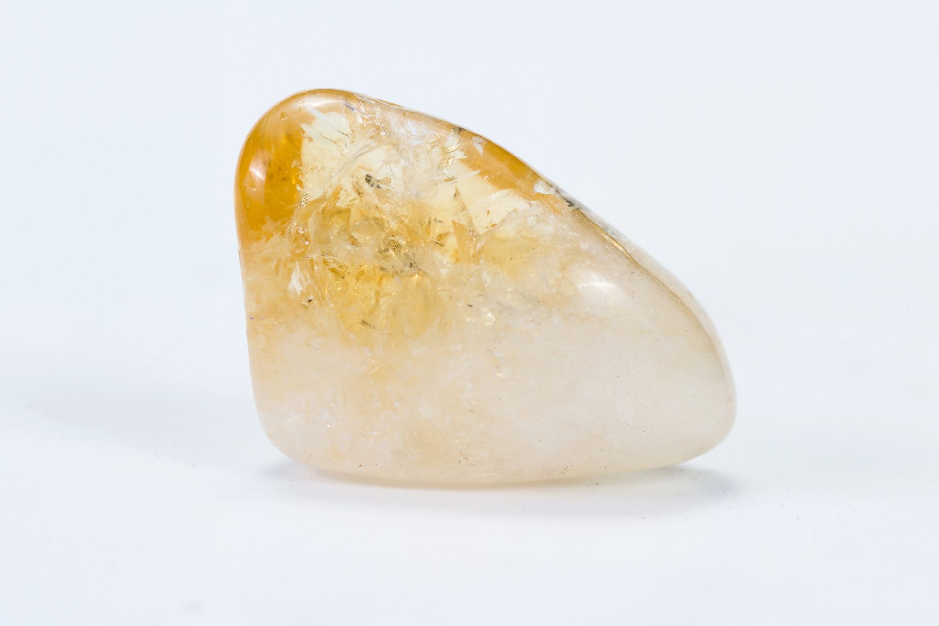 Piedra lisa blanca y ámbar pulida sobre un fondo claro.