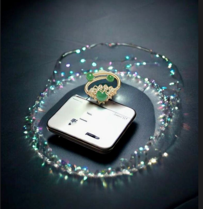 Pequeño dispositivo blanco con un dije en forma de corazón, rodeado por un rastro circular brillante sobre un fondo oscuro.