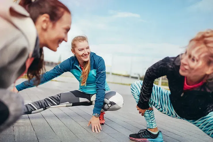 3 women stretch their legs outside