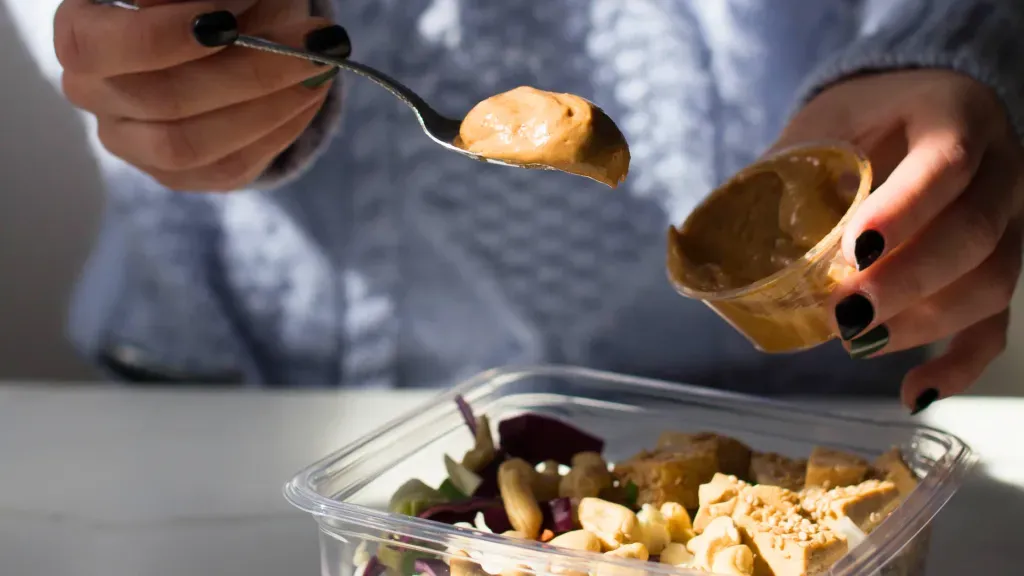 A person spreads salad dressing over their salad