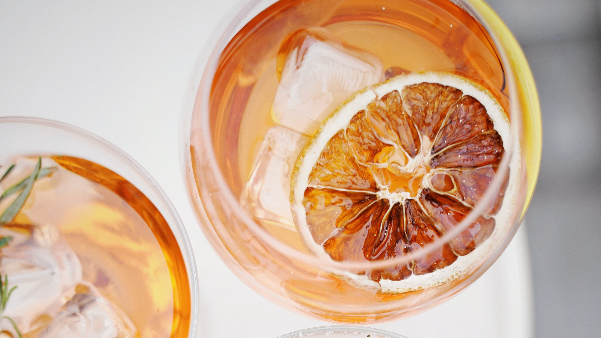 An aerial view of a glass of an orange-coloured mocktail and a lemon inside