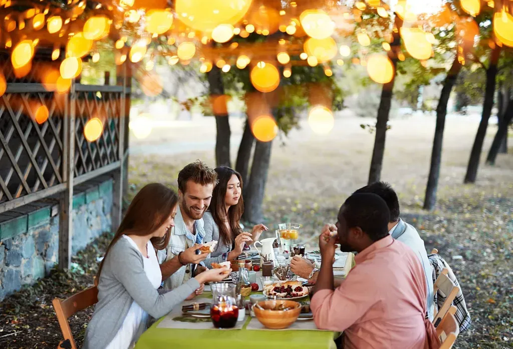 A group of friends sit at a picnic table and eat food