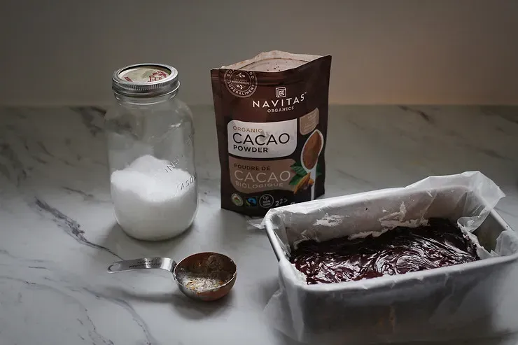 Chocolate mint bars in container next to cocao powder and sugar in a mason jar