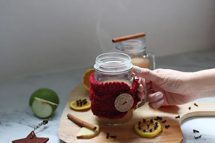 A person is holding a glass mug of tea
