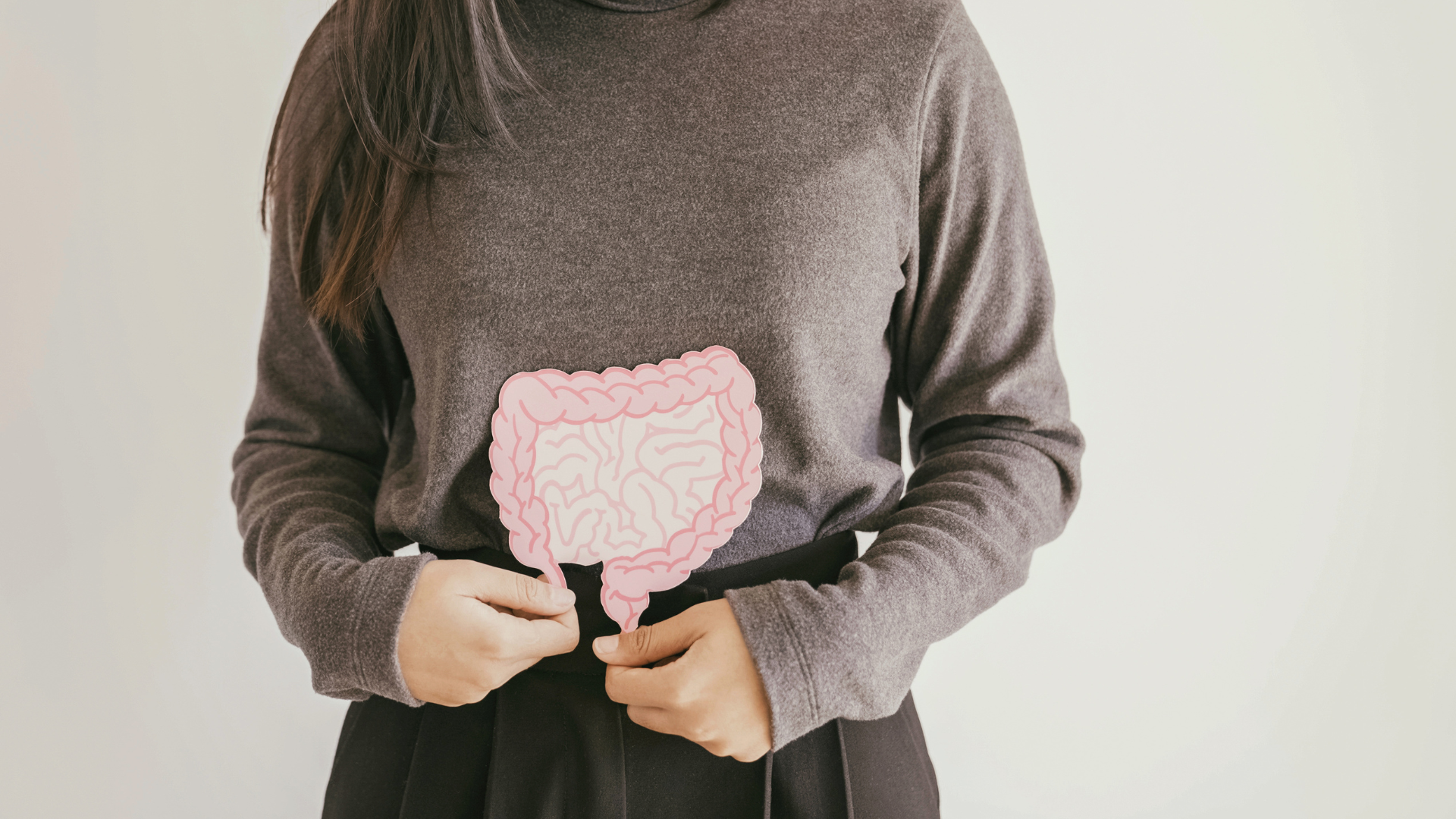 A woman holding a cardboard cutout of the intestines over her body