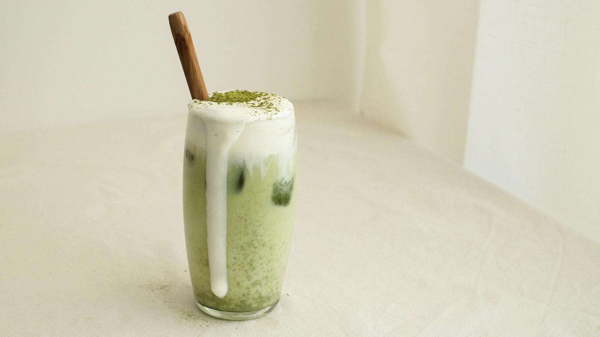 A tall glass containing a mocha-flavoured beverage, which is overflowing out of the glass. A cinnamon stick sits on top.