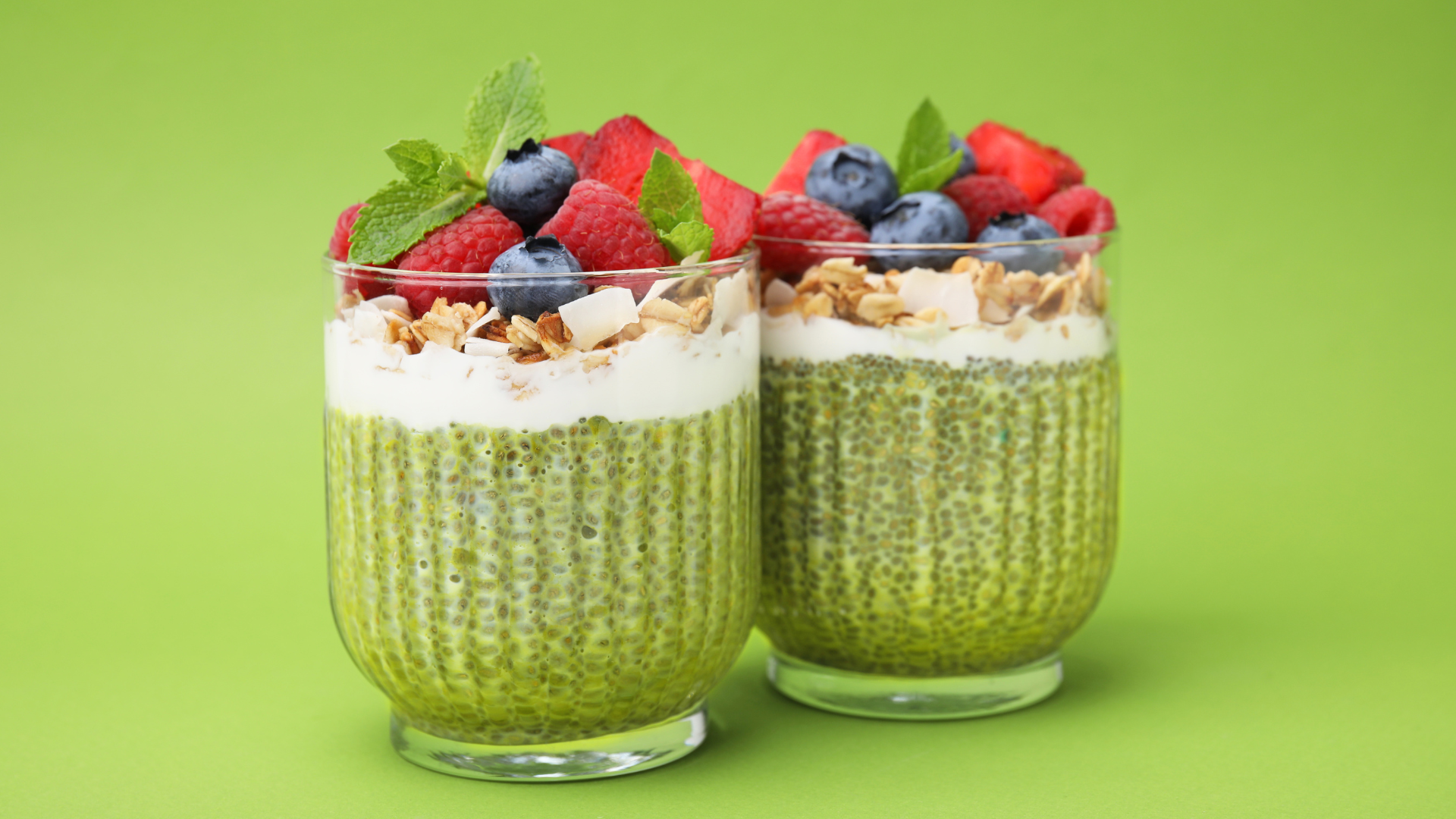Two glasses of Chia Pudding with Bluberries and Strawberries surrounding the top