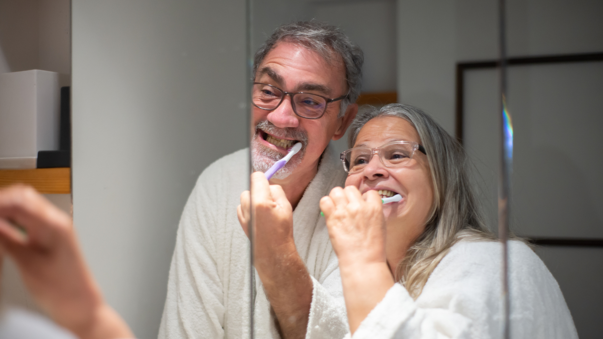 Two elderly people brushing their teeth