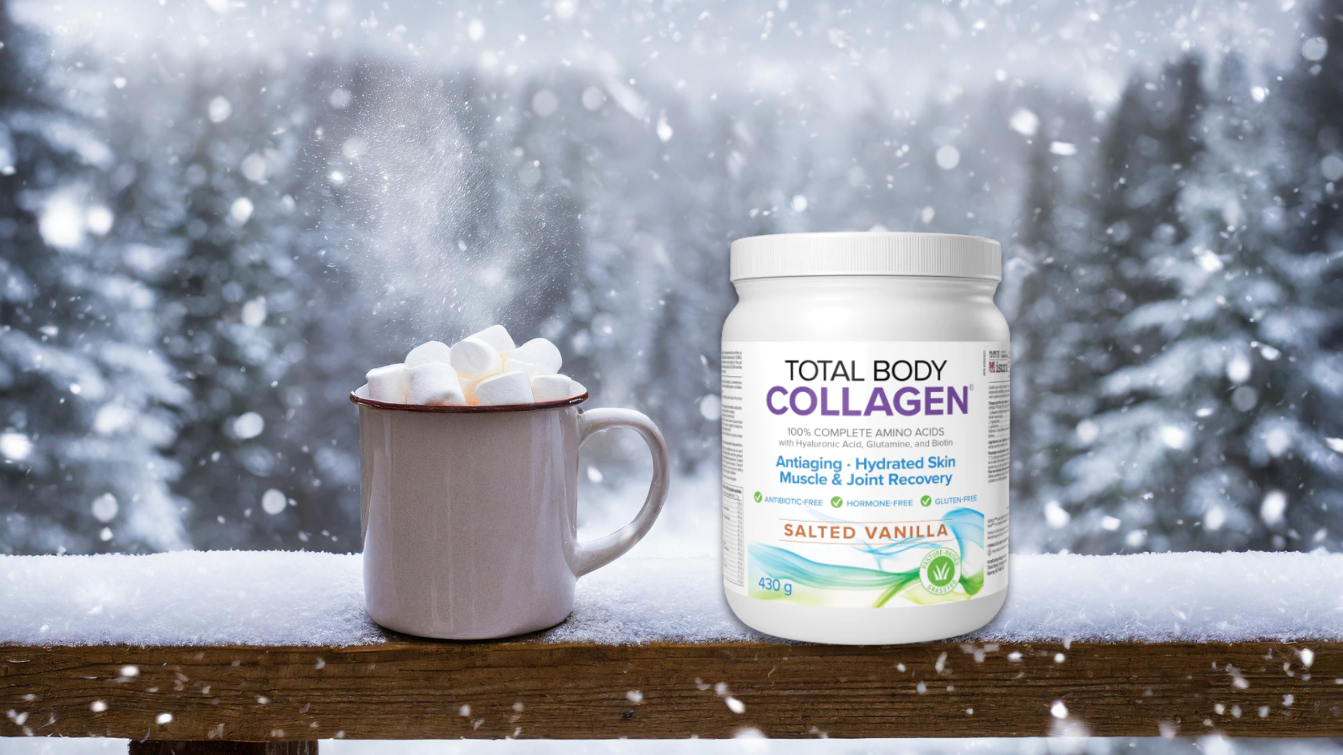 A grey mug overflowing with hot chocolate and marshmallows sits on a snowy ledge next to a container of Total Body Collagen