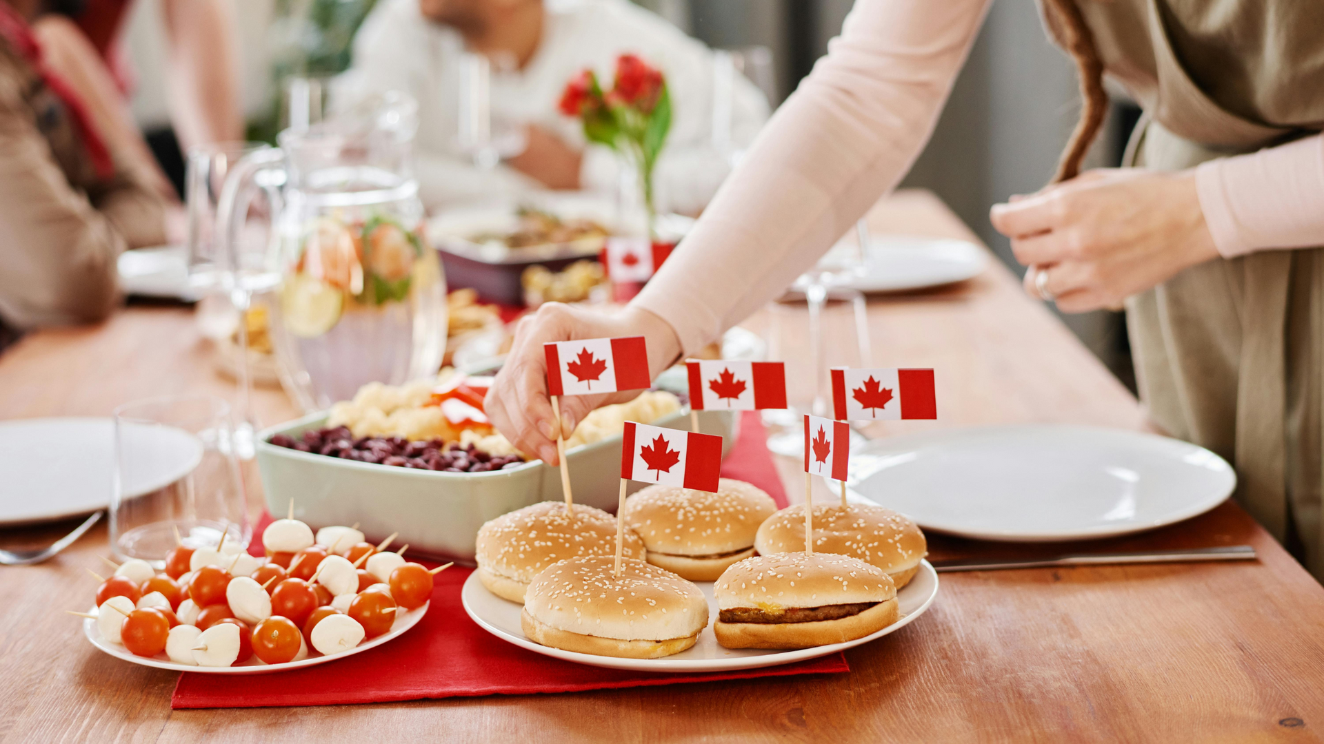Tiny Canadian flags are pinned into cooked burgers and an entire picnic setup with all kinds of food