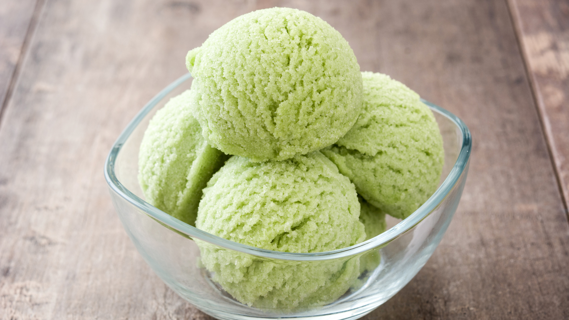 Green ice cream scoops sit in a clear bowl