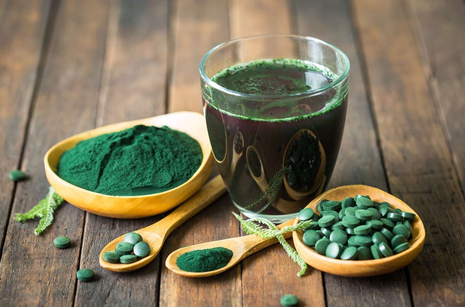 The powdered, pill and liquid forms of spirulina sitting on a table.  