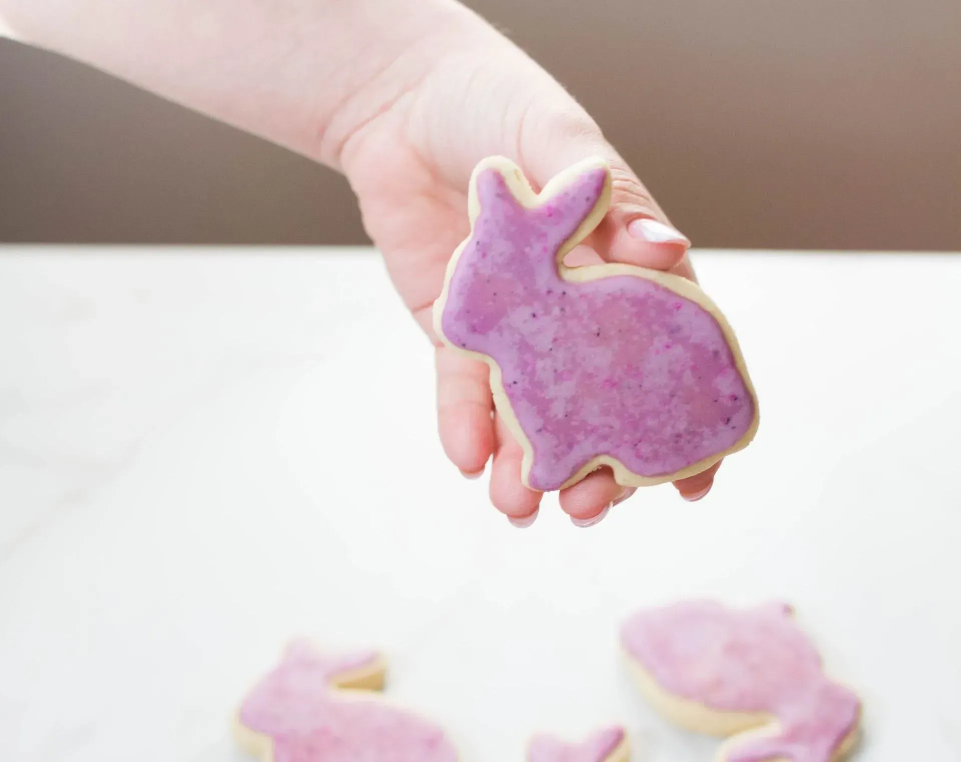 A person holds up a cookie treat in the shape of a bunny