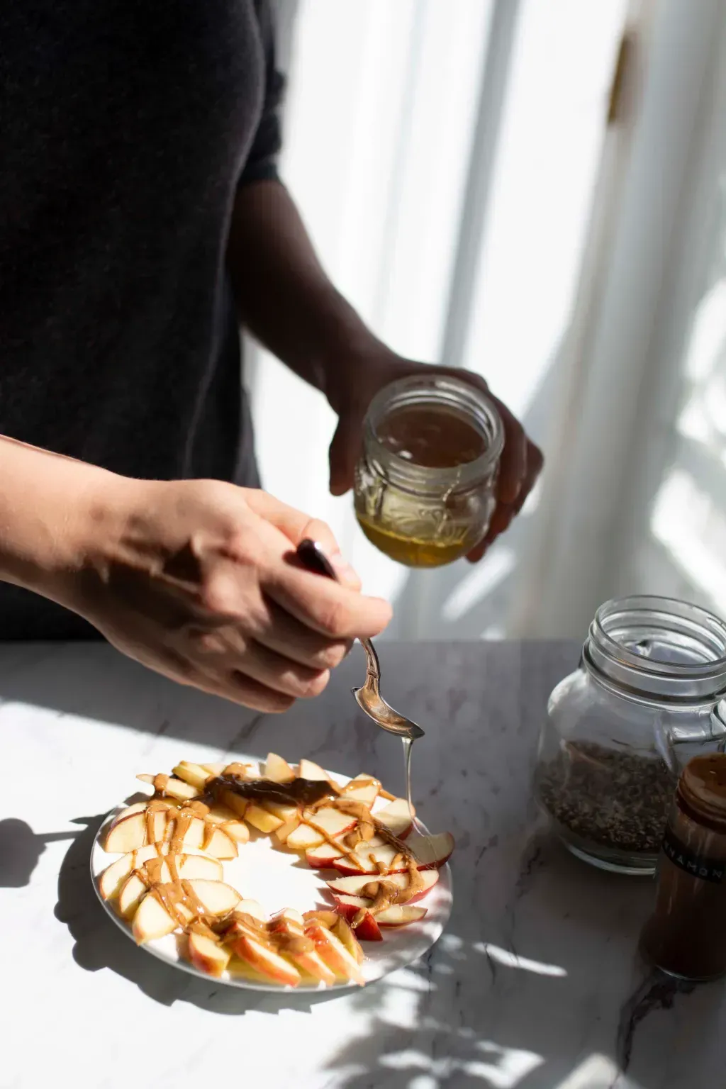 A person pours honey over apples using a spoon