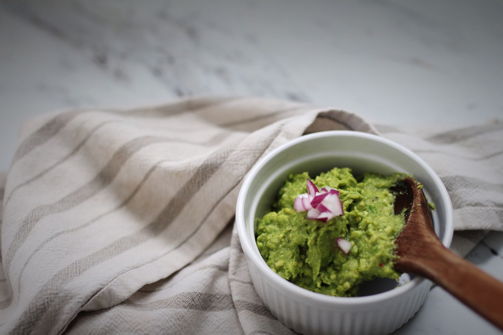 Guacamole is stirred in a small bowl with a wooden spoon