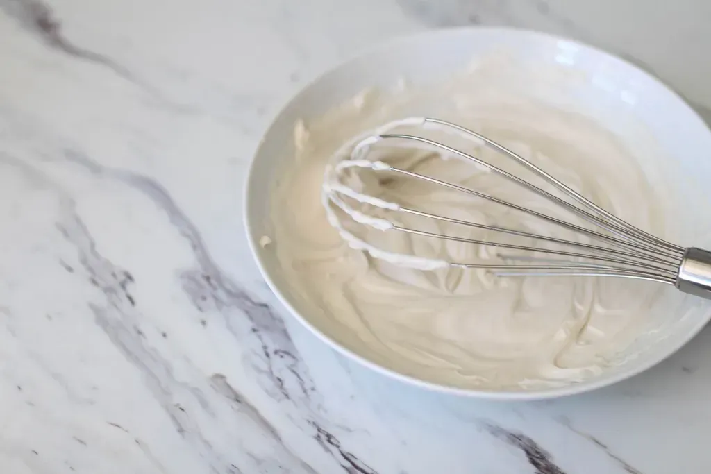 cream in a bowl with a whisk