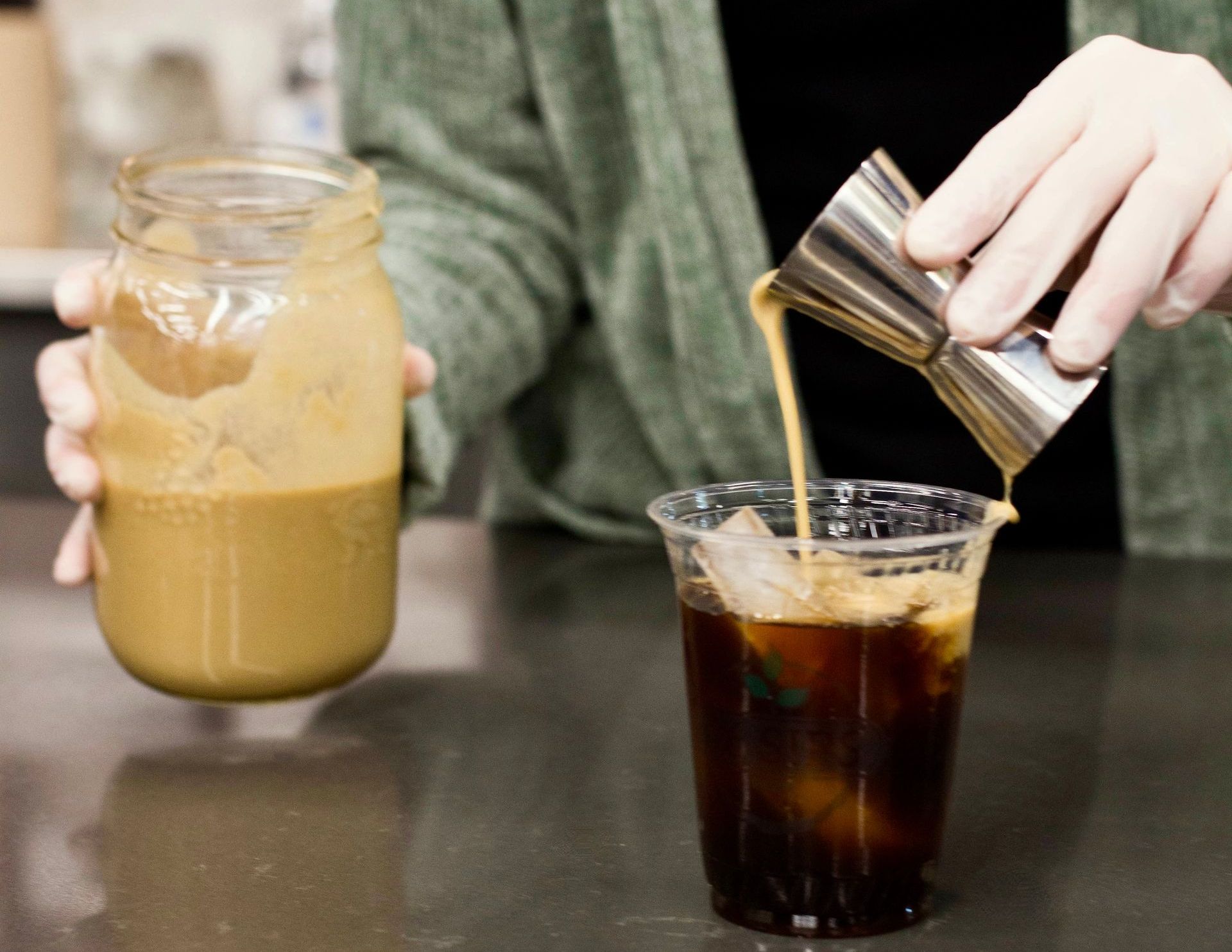 Barista pouring irish cream on a cup of cold brew