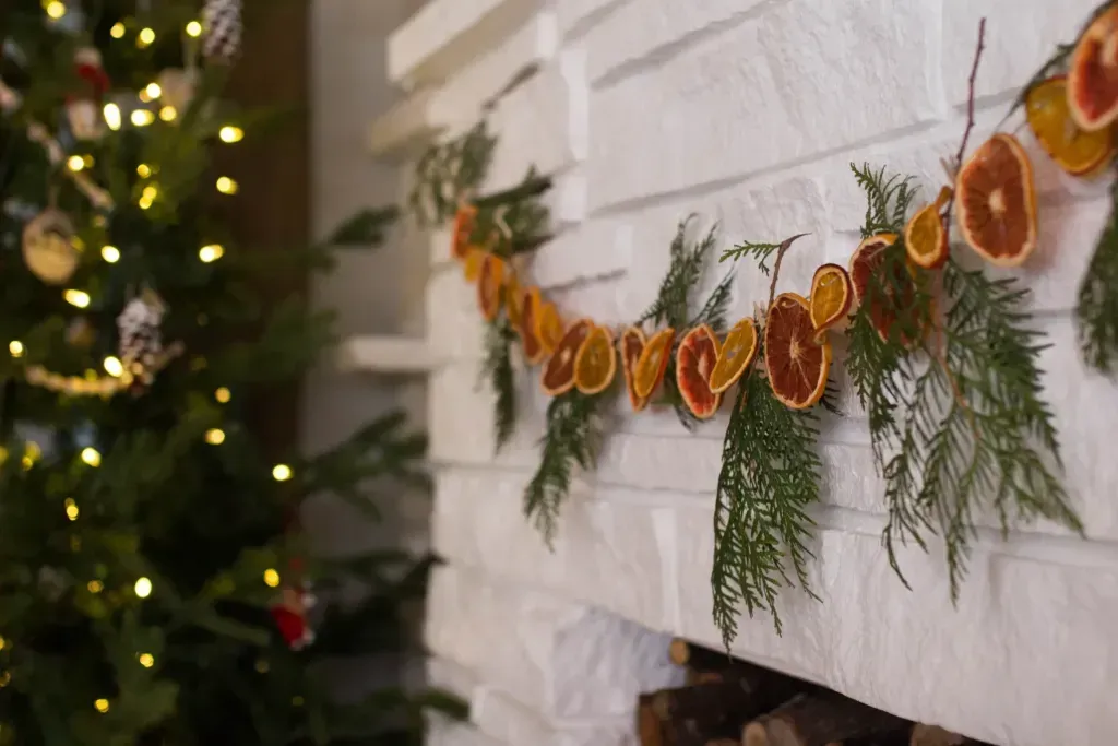 Citrus fruits hang above a fireplace with foliage surrounding it