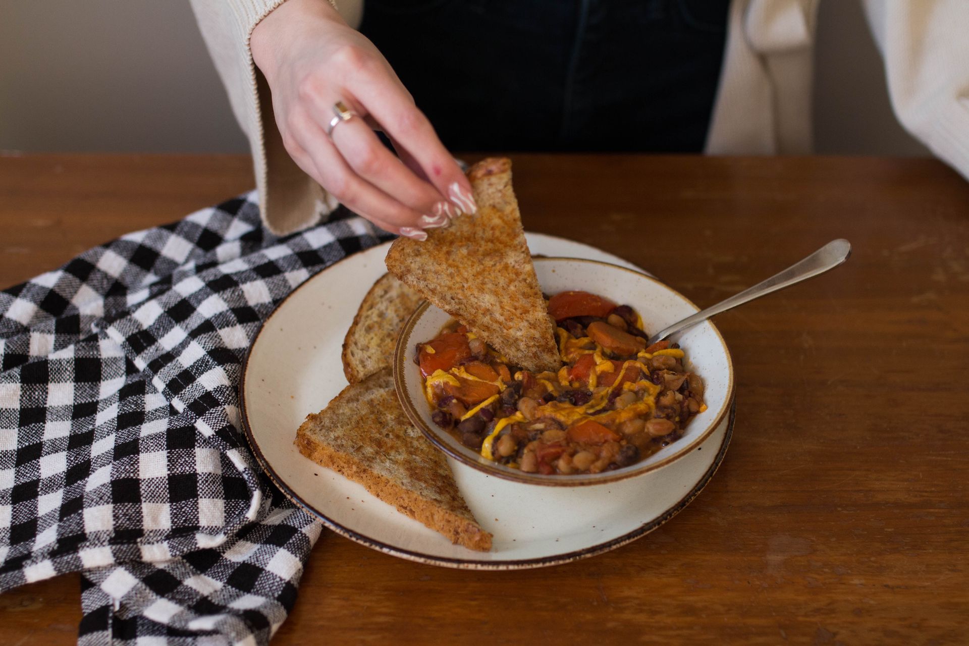 A person dips a piece of toast into a stew