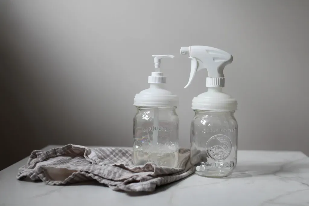 Cleaning bottles sit on a table under a towel