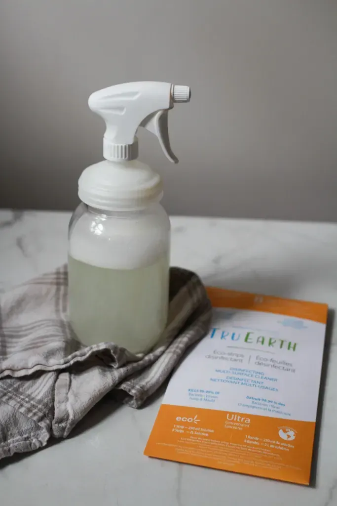 A bottle of cleaner sits under a towel on a table