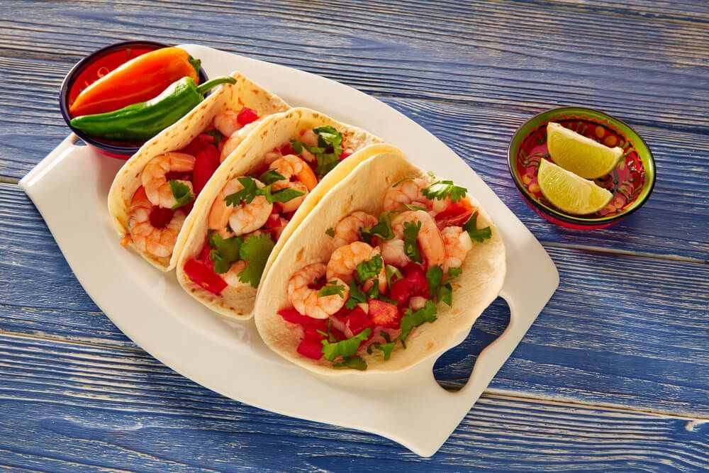 Spicy Baja Style Shrimp Tacos sitting on a dish with lemons next to it