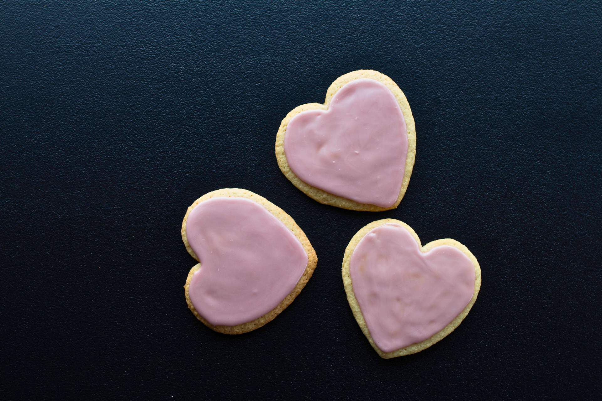 3 heart shaped cookies sit on a table
