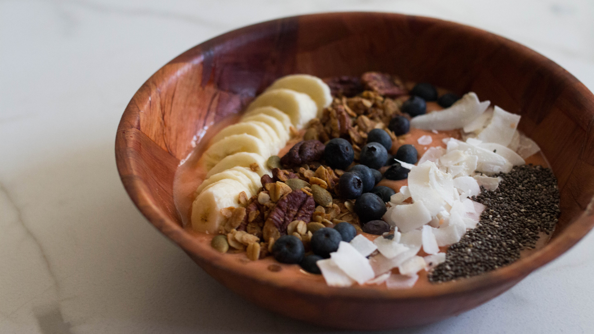 Various fruits and nuts sit in a wooden bowl