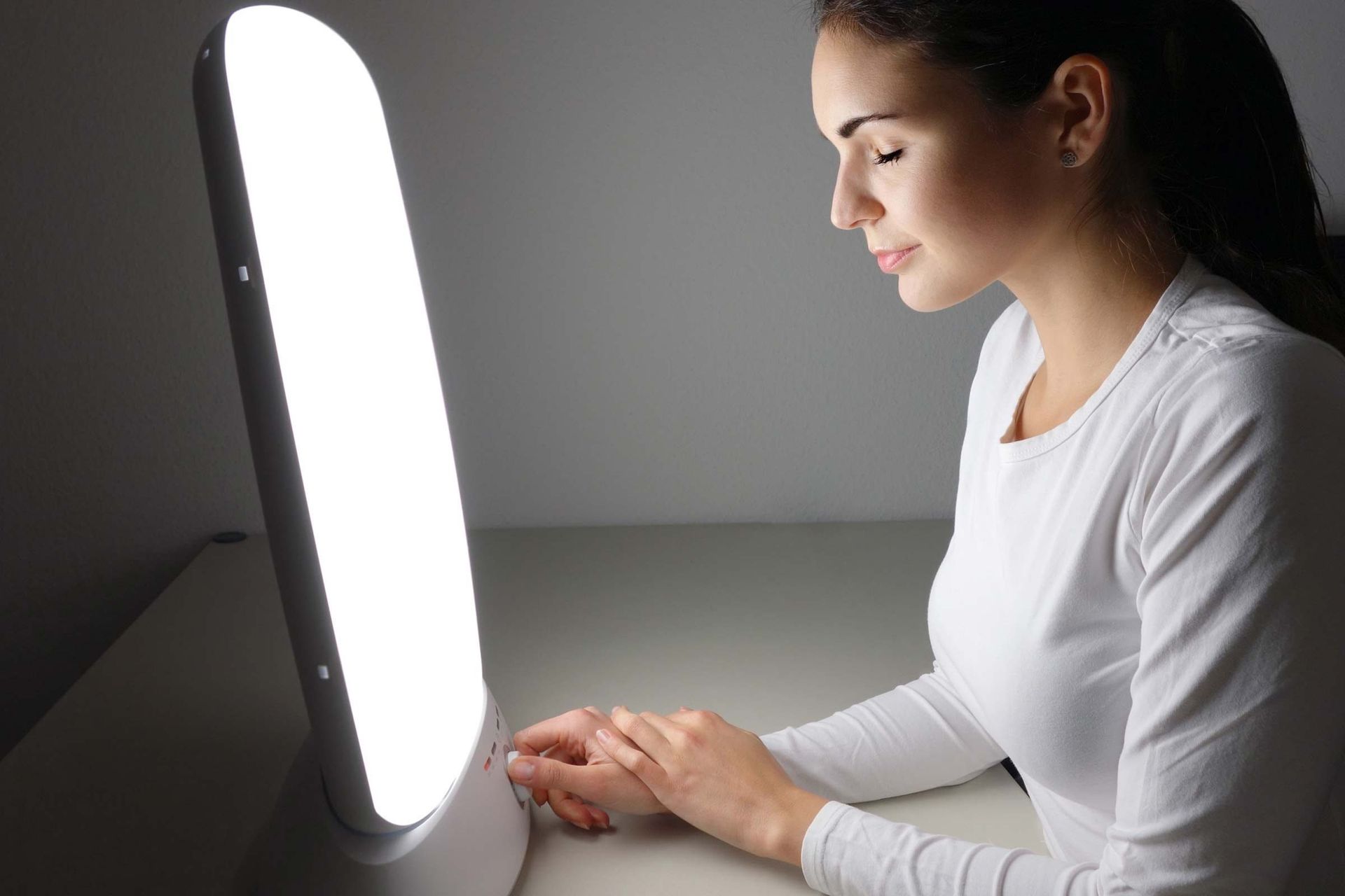 A woman sits in front of her light therapy lamp