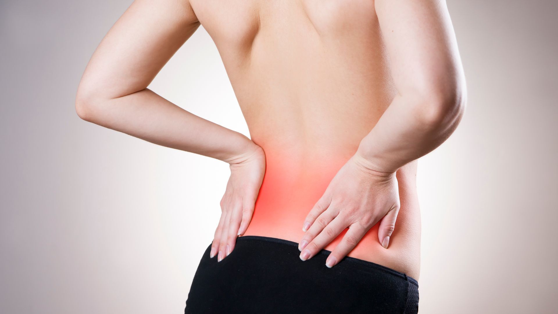 a woman holding her lower back which is coloured red to indicate inflammation